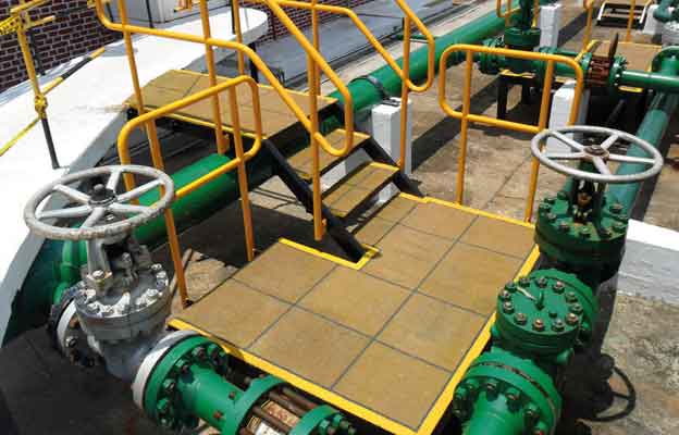 Plataforma industrial con piso antideslizante junto a tubería de proceso